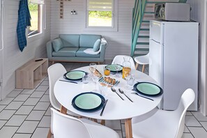 Une cuisine moderne avec un coin repas, des appareils électroménagers blancs et un canapé de couleur turquoise.