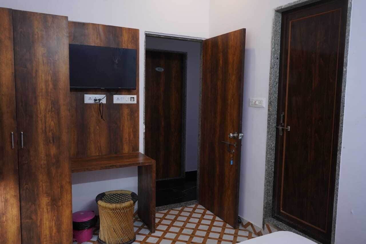A room with wooden wardrobes, a television, a door, and a tiled floor.