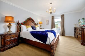 A well-appointed bedroom with a wooden bed, two bedside tables, a chandelier, and a television. - Wish Upon A Star in Kissimmee (Kissimmee)