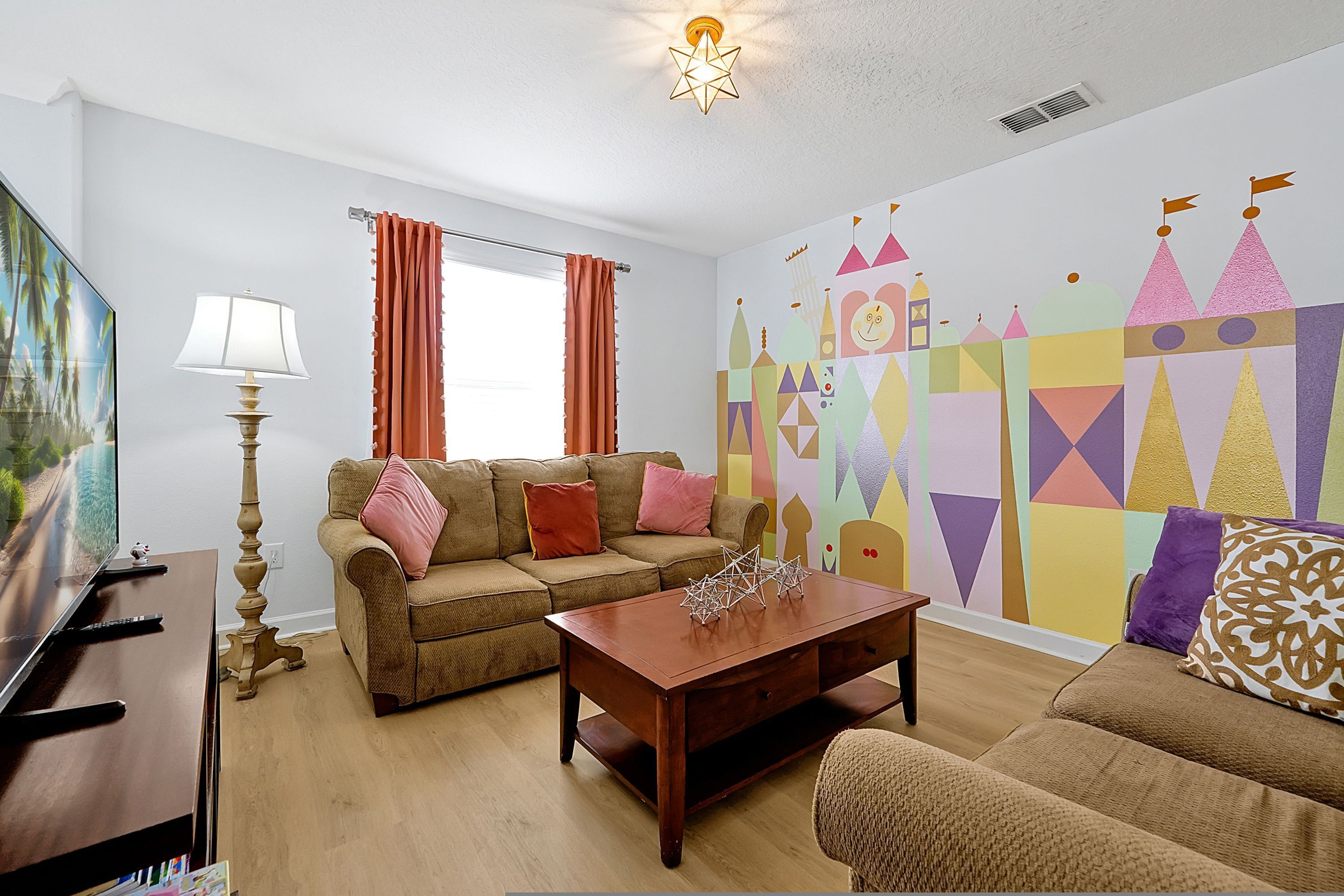Ein Wohnzimmer mit einer Couch, einem Couchtisch, einer Lampe und einer Wand mit geometrischen Mustern.