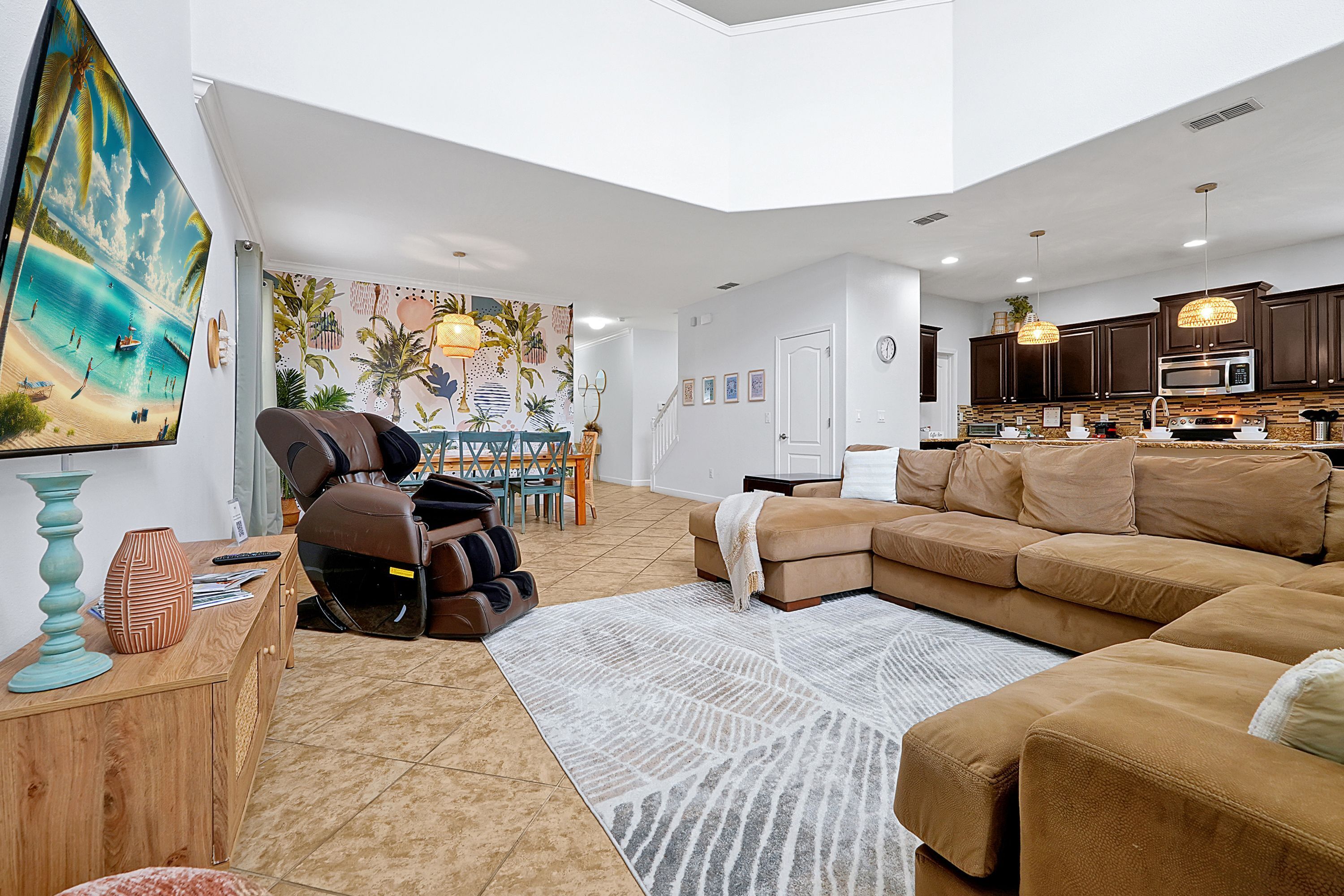 A spacious living room with a large sectional sofa, a massage chair, and a dining area with a table and chairs.