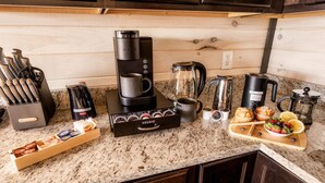A kitchen with a coffee maker, coffee grinder, kettle, and various coffee pods. - Skydeck Pinnacle in Sevierville (Sevierville)