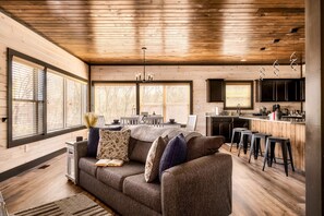Una sala acogedora con sofá, comedor y cocina con taburetes de bar.
