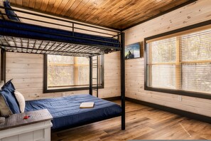Una habitación con literas, un escritorio y una ventana con persianas.