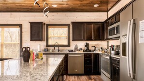 A modern kitchen with dark cabinets, stainless steel appliances, and a granite countertop. - Skydeck Pinnacle in Sevierville (Sevierville)