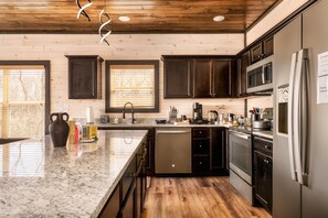 A modern kitchen with dark cabinets, stainless steel appliances, and a granite countertop. - Skydeck Pinnacle in Sevierville (Sevierville)