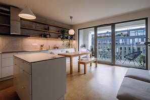 A modern kitchen with a dining area, large windows, and a view of the city. - ♡ Family apartment, 3 bedrooms, parking, prime location (Praha)