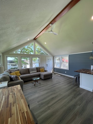 A spacious living room with a large sectional sofa, a wooden coffee table, and a dining table.