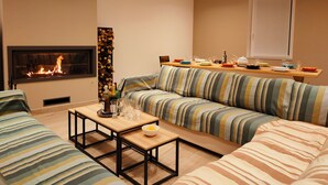 A living room with a sofa set, a coffee table, a fireplace, and a dining area with a table set for a meal.