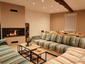A living room with a sofa set, a coffee table, a fireplace, and a dining area with a table set for a meal.