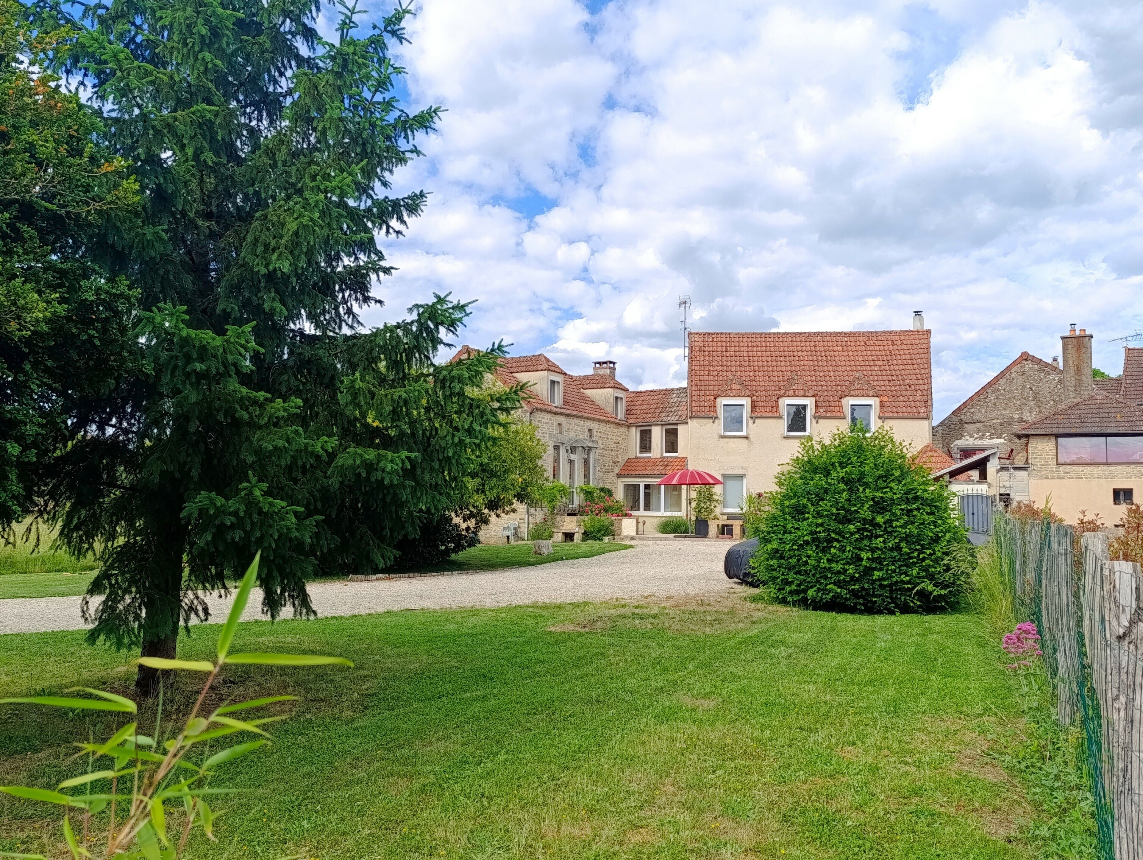 A residential area with a stone house, a gravel driveway, and a well-maintained lawn.