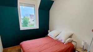 A bedroom with a bed, a nightstand, a window, and a ceiling light fixture.