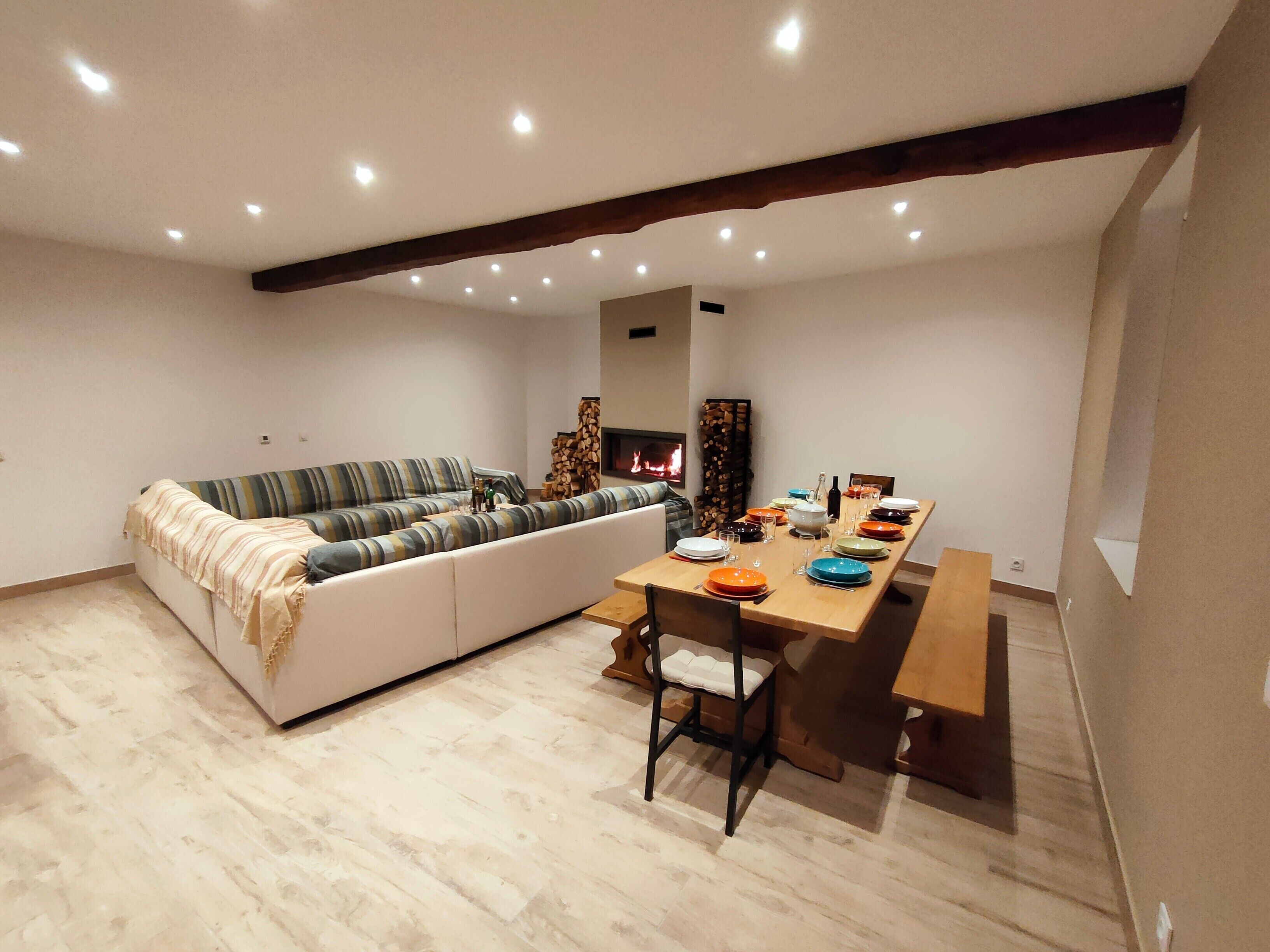 A modern living room with a sofa, a dining table set for four, and a fireplace.
