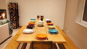 A dining table set with various plates and glasses, a wooden bench, and a chair with a cushion.
