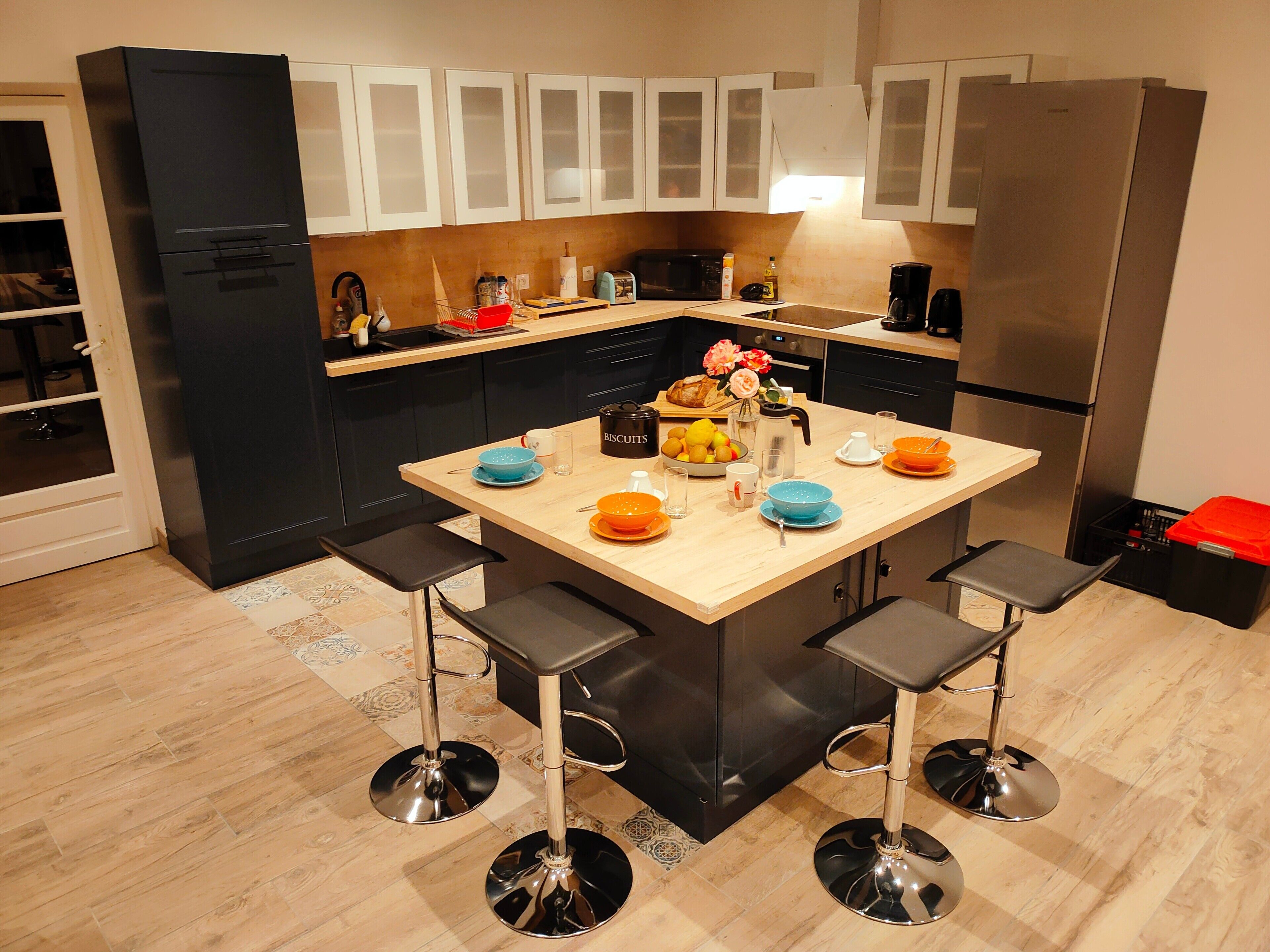 A modern kitchen with a central island, bar stools, and stainless steel appliances.