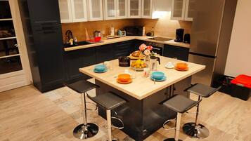 A modern kitchen with a central island, bar stools, and stainless steel appliances.