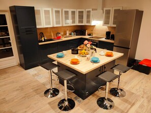 A modern kitchen with a central island, bar stools, and stainless steel appliances.