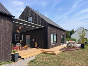 A modern house with a wooden exterior, a covered porch with seating, and a garden area. - TyGwenHaJu (Plounéour-Brignogan-plages)