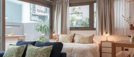 Une chambre d’hôtel avec un lit, un canapé, un bureau et une fenêtre avec des rideaux.