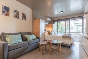 A modern living room with a sofa, a small round table, and a bed with a view to the outside. - Scala I - Premium Apartment in Palermo Soho (Buenos Aires)