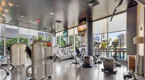 Ein modernes Fitnessstudio mit Cardiogeräten, Kraftstationen und einem großen Fenster mit Blick auf die Stadt.