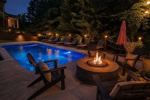 Ein Pool mit Liegestühlen und einem Bereich mit Feuerstelle.