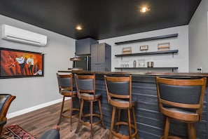 Eine moderne Küche mit Barbereich, ausgestattet mit Holzbarhocker, einem Kühlschrank und einem Bild an der Wand.