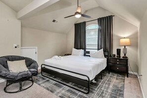 A bedroom with a bed, a chair, a nightstand, and a lamp. - Luxury Chapin Retreat | Pool, Theater, Gym + Bar (Chapin)