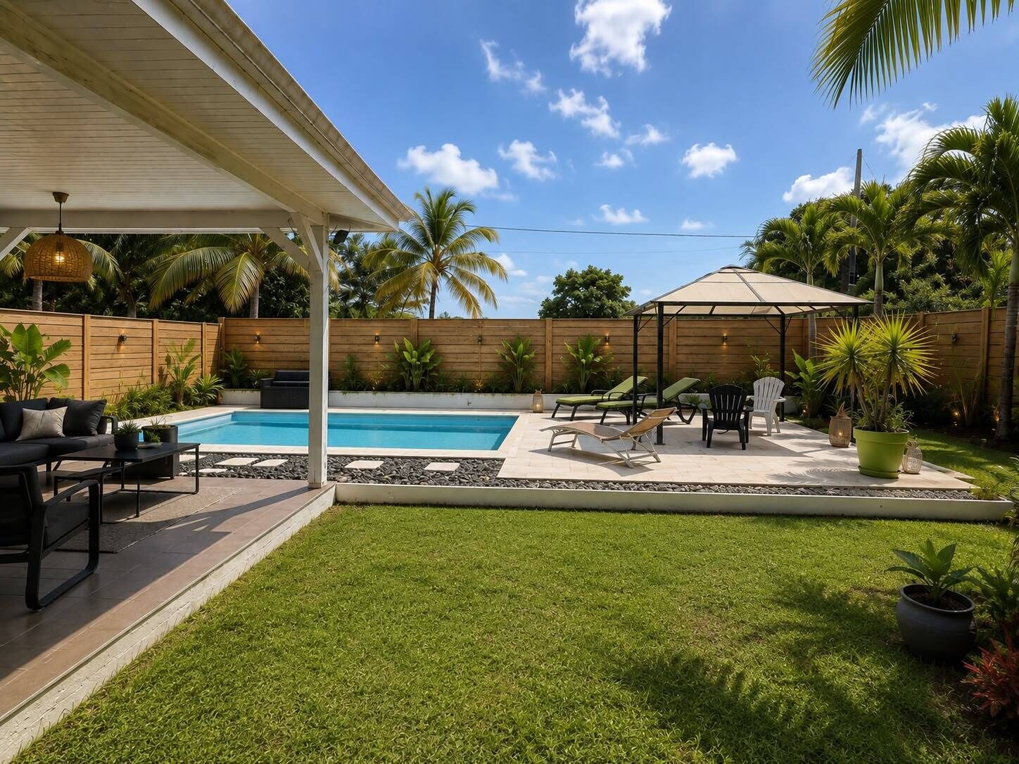 Un jardin avec une piscine, un espace salon extérieur et une clôture en bois.