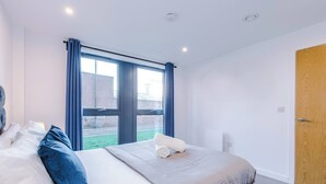 A hotel room with a large bed, a window with curtains, a wooden door, and a view of the outside. - #82 Stylish Shirley Home Sleeps 8 NEC Solihull BHX (Shirley)