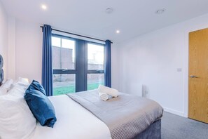 A hotel room with a large bed, a window with curtains, a wooden door, and a view of the outside. - #82 Stylish Shirley Home Sleeps 8 NEC Solihull BHX (Shirley)