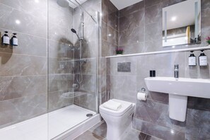 A modern bathroom with a glass-enclosed shower, a white toilet, and a sink with toiletries. - #82 Stylish Shirley Home Sleeps 8 NEC Solihull BHX (Shirley)