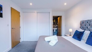 A hotel room with a bed, a nightstand, a lamp, a door, and a view of a bathroom. - #82 Stylish Shirley Home Sleeps 8 NEC Solihull BHX (Shirley)