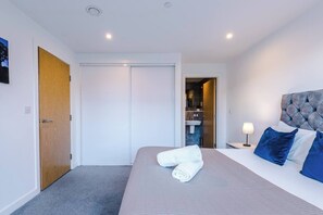 A hotel room with a bed, a nightstand, a lamp, a door, and a view of a bathroom. - #82 Stylish Shirley Home Sleeps 8 NEC Solihull BHX (Shirley)