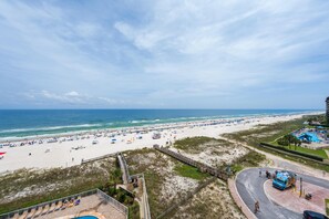 Ein Strand mit Poolbereich, einem Promenadenweg und Blick aufs Meer.