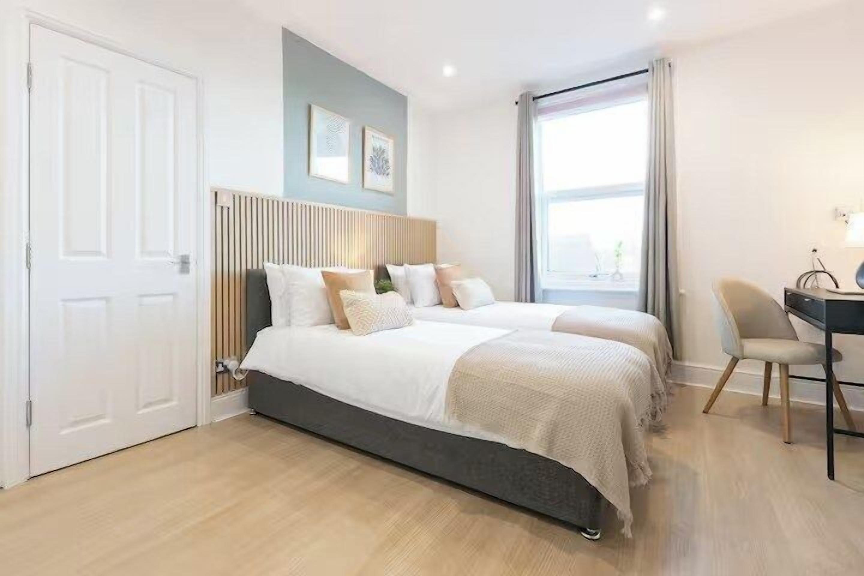 A bedroom with a bed, bedside tables, a desk, and a chair.