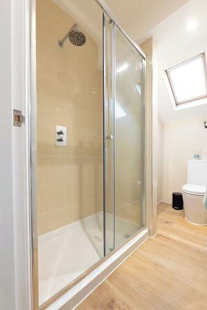 A bathroom with a glass-enclosed shower, a toilet, and a window above the sink. - Spacious 2BR Near Leeds Centre – Free Parking (Leeds)