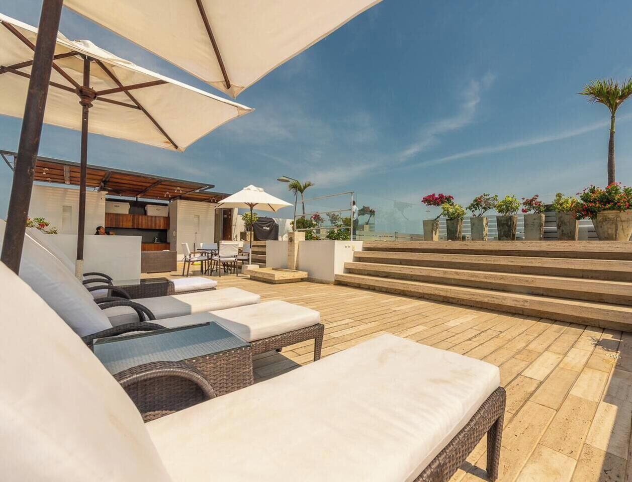 Una terrassa al terrat amb gandules, una zona de bar i vista al mar.