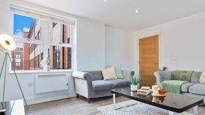 A modern living room with a large window, two sofas, a coffee table, and a door. - #90 The Lux Mint apartment JQ (West Midlands)