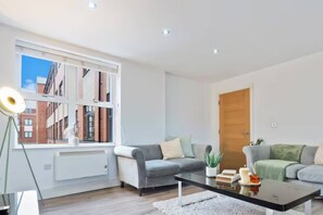 A modern living room with a large window, two sofas, a coffee table, and a door. - #90 The Lux Mint apartment JQ (West Midlands)