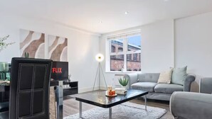 A modern living room with a sofa, a coffee table, a television, and a floor lamp. - #90 The Lux Mint apartment JQ (West Midlands)