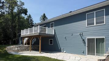 A two-story house with a wooden deck and stone steps leading to a front door.