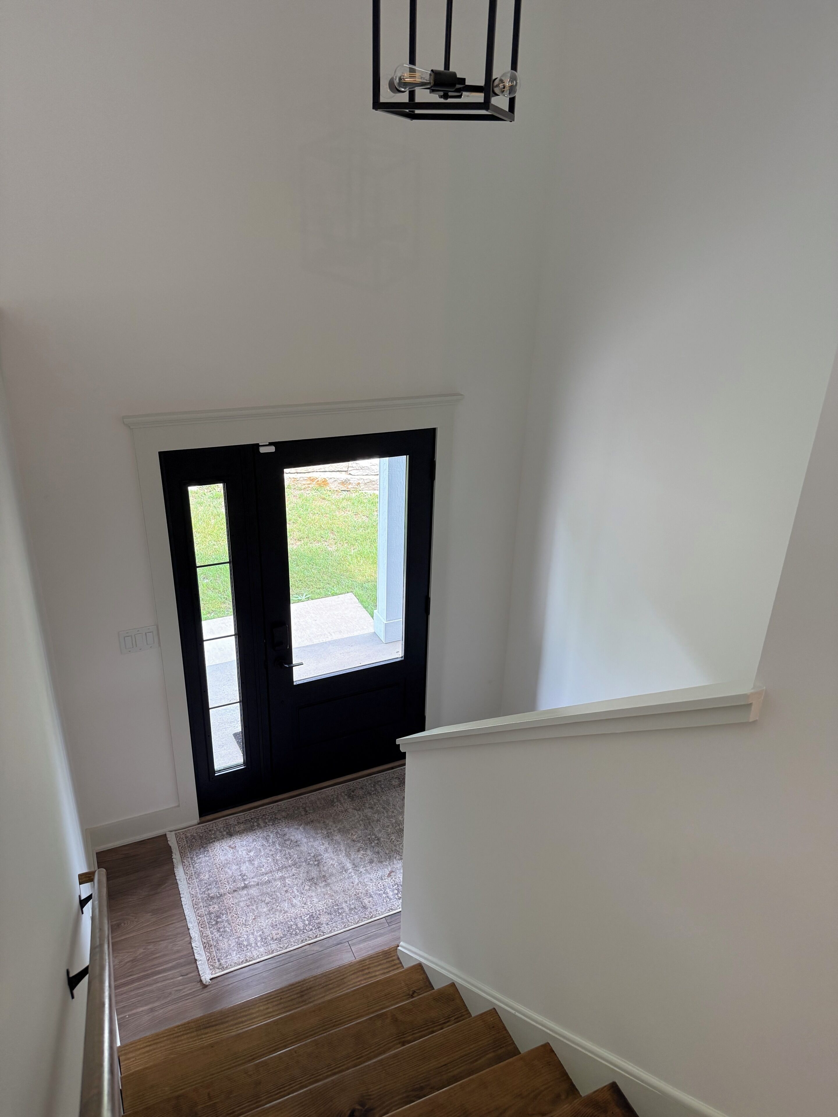 A staircase leading to a door with a view of a lawn outside.