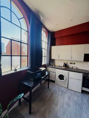 A compact kitchen with a large window, a washing machine, and a microwave. - #84 Large JQ apartment sleeps 9 (West Midlands)