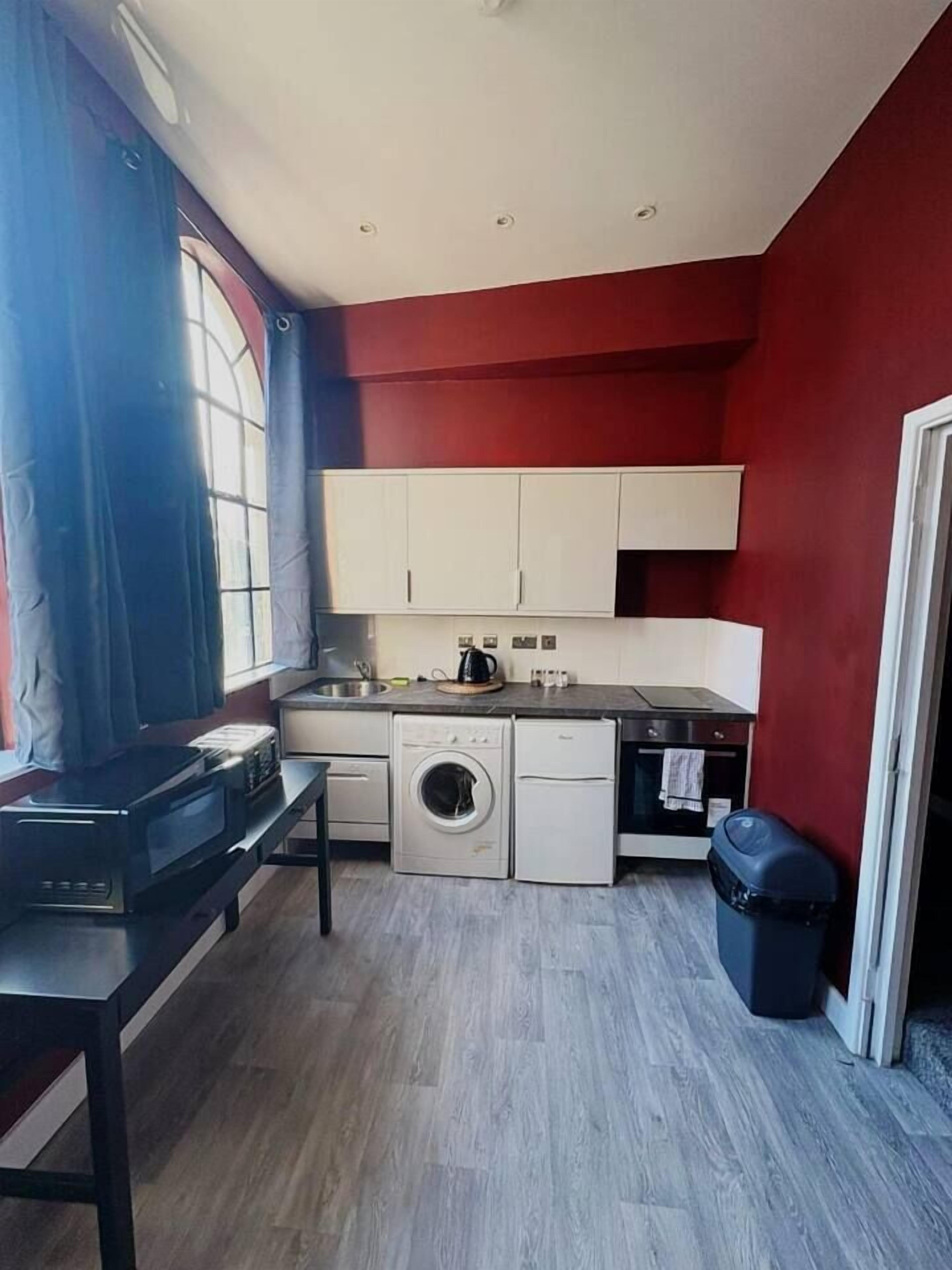 Een functionele keuken met een wasmachine, een broodrooster en een kleine oven.