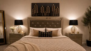 Un dormitorio con una cama grande, dos mesitas de noche, un cabecero y una obra de arte colgada en la pared.