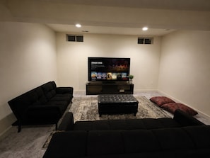 A living room with a flat-screen TV, two black sofas, a coffee table, and a patterned rug. - Spacious studio by the woods (Laurel)
