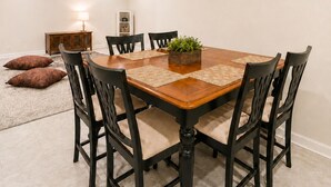 Un comedor con mesa de madera, sillas negras y un pequeño centro de mesa con planta.