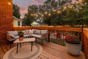 Une terrasse en bois avec un canapé, une petite table et une plante en pot.