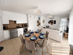 A modern kitchen with white cabinetry, a dining area with a round table, and a living space with a sofa.
